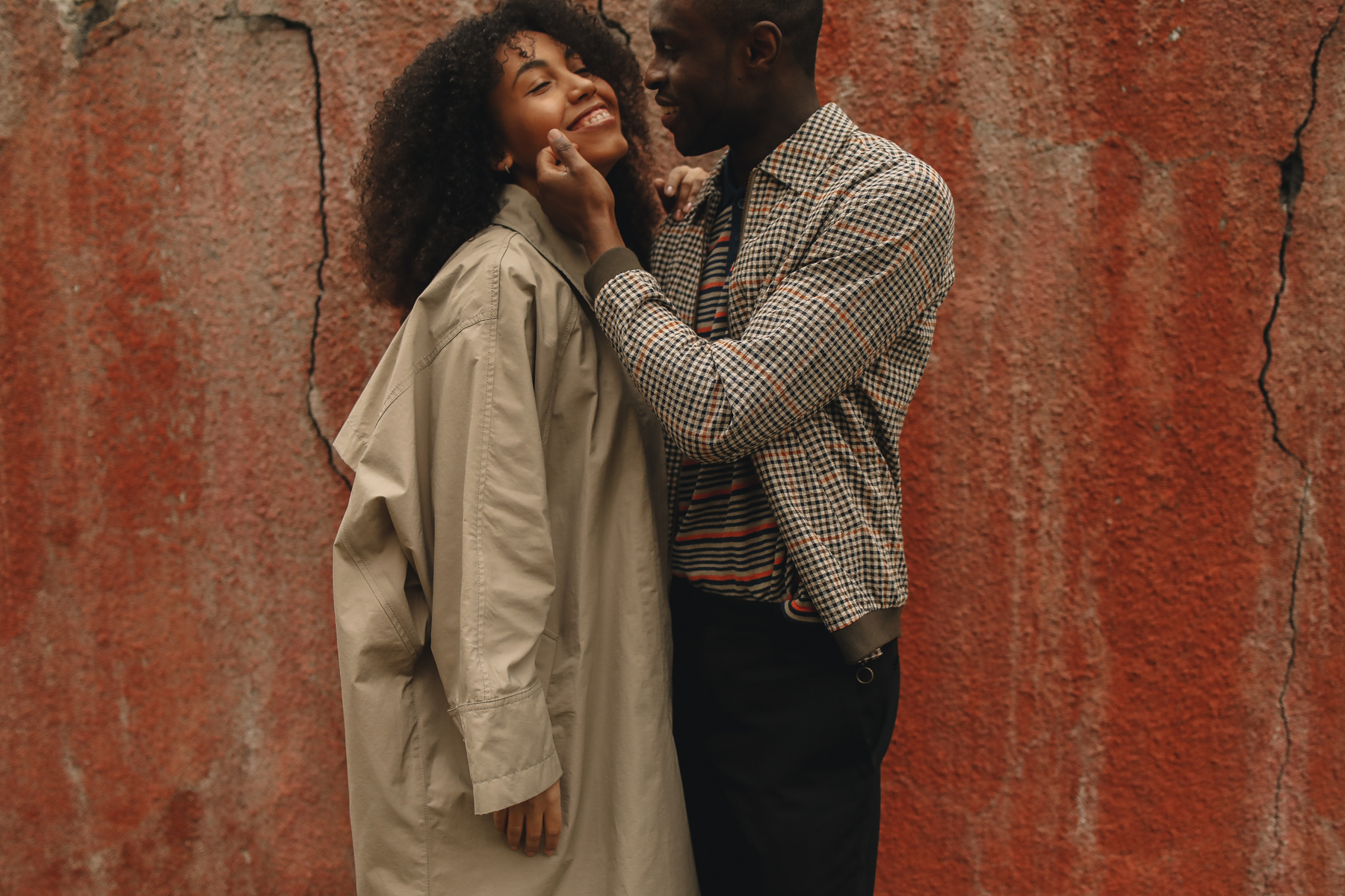 Happy Couple Standing Near A Red Wall