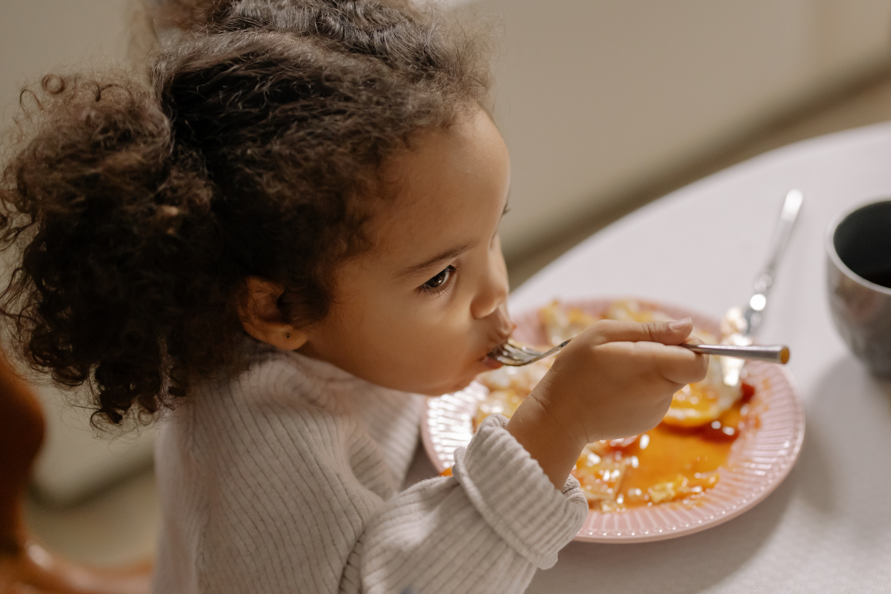 Close-Up Photograph of a Child with Curly Hair Eating